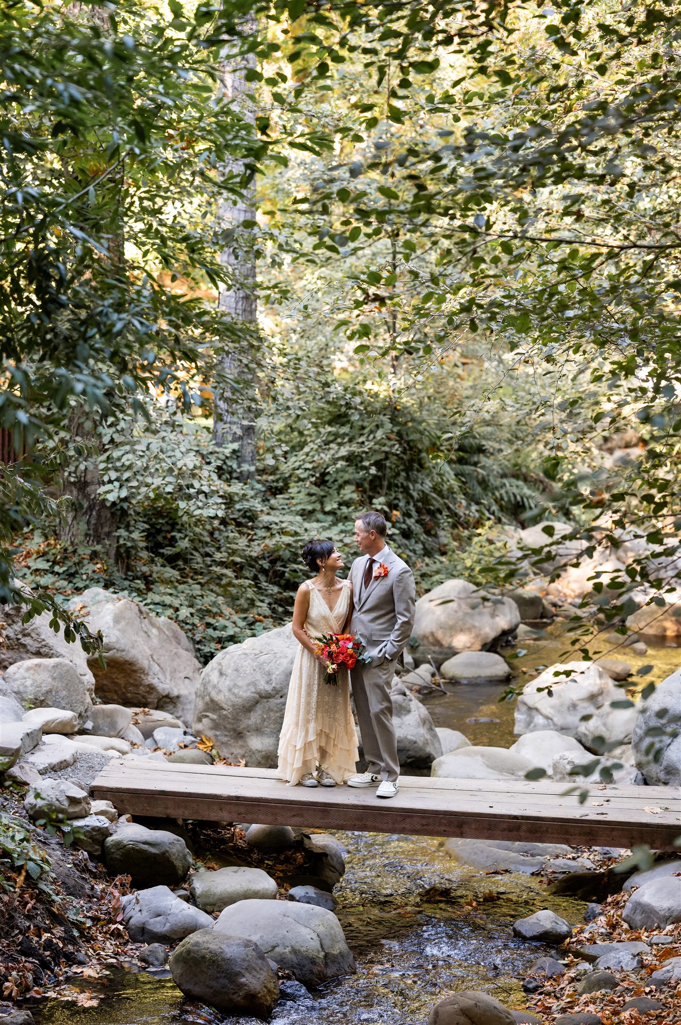 Bride and Groom standing on a bridge in the woods at Saratoga Springs